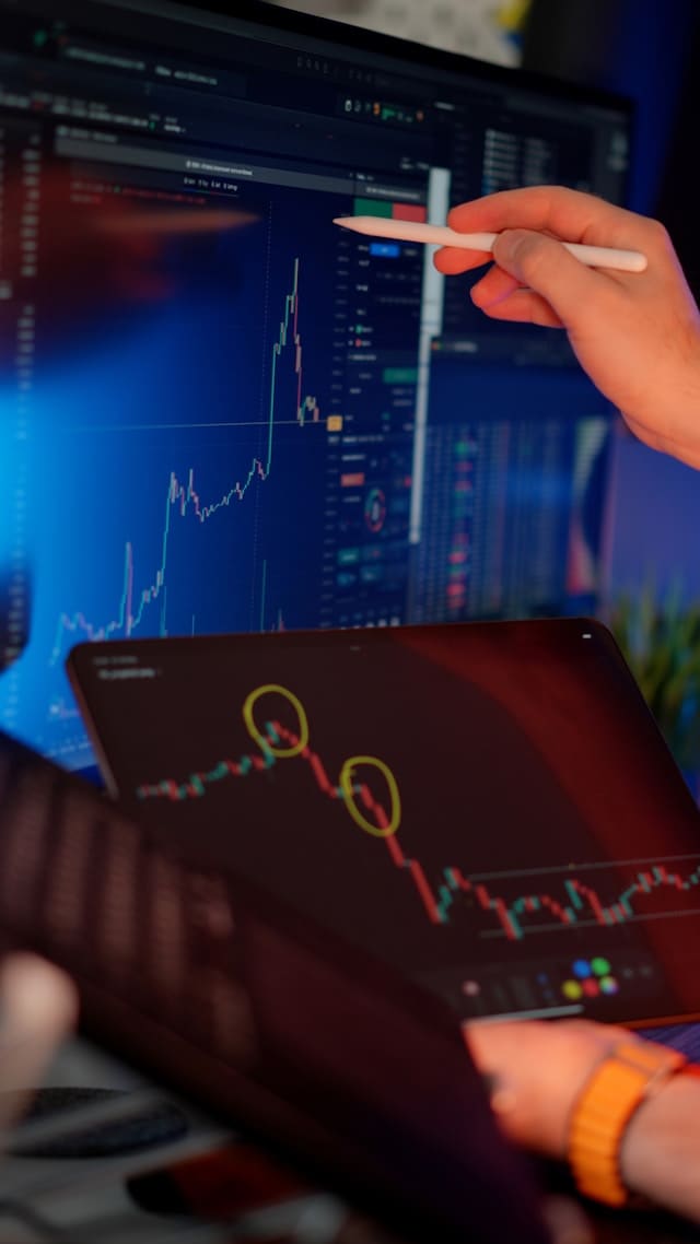Mano señalando con un lápiz digital un gráfico de velas en una tableta